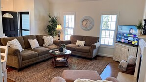 A living room with two brown sofas, a coffee table, a TV, and a clock on the wall. - Cozy home near RDU, RTP, Angus Barn & downtown! Pet Friendly! Level-2 EV Charger (Raleigh)