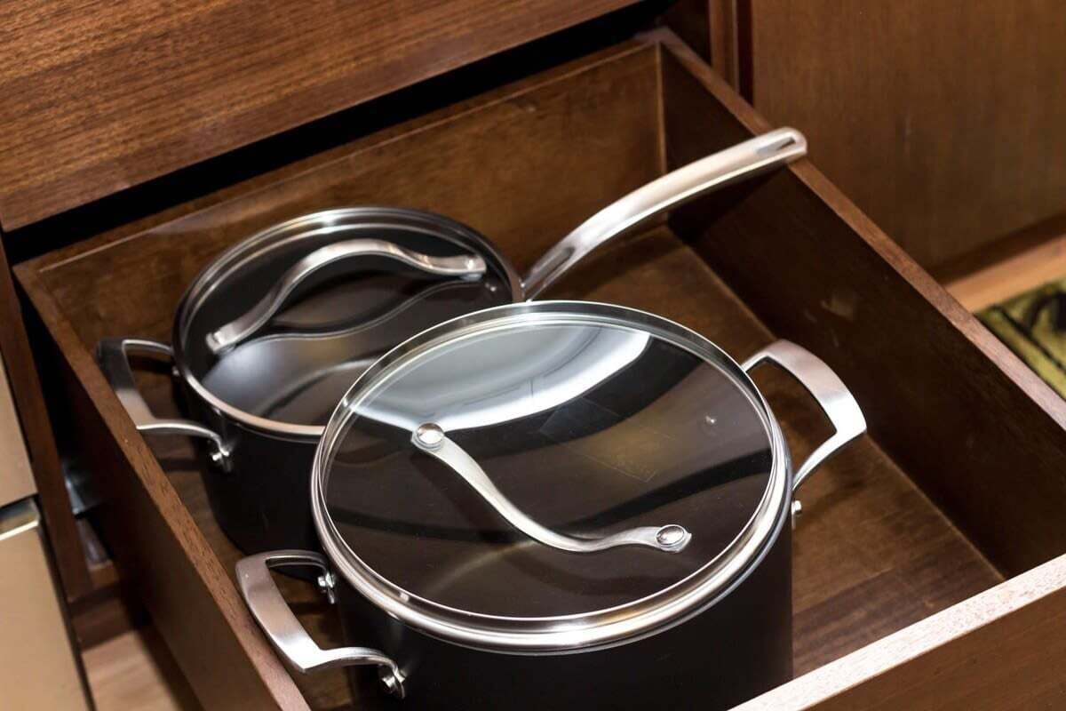A drawer with two black pots with lids.