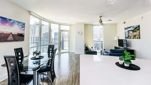 Uma sala de estar moderna com área de jantar, janelas amplas e vista para a cidade.