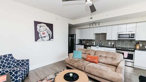 Een moderne woonkamer met een bank, een rond salontafeltje en een plafondventilator.
