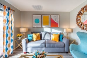 A modern living room with a grey sofa, two side tables with lamps, and a decorative mirror.