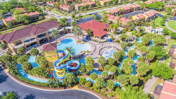 Vista aérea de un complejo turístico con un área de piscina central, múltiples piscinas y un parque acuático.