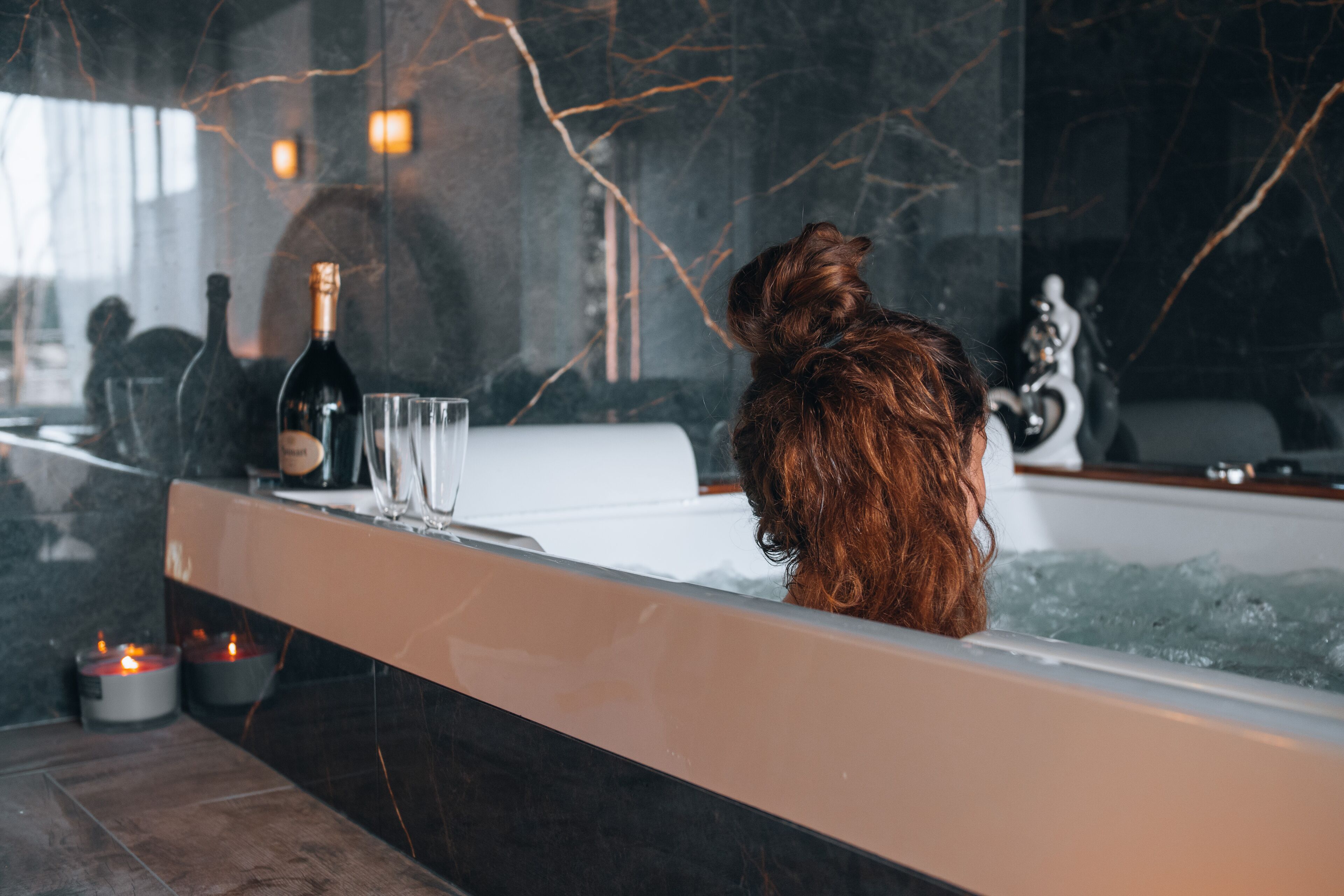 A bathtub with a bottle of champagne, two glasses, and candles.