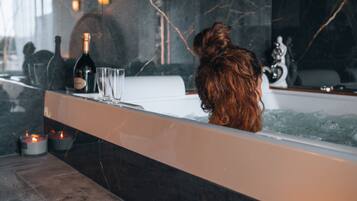 A bathtub with a bottle of champagne, two glasses, and candles.