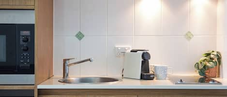 Une cuisine équipée d’un four à micro-ondes, d’un grille-pain, d’un évier et de placards.
