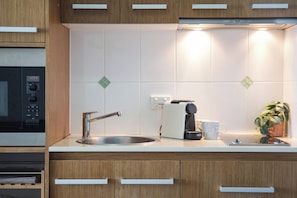 A kitchen with a microwave, toaster, sink, and cabinets. - Pacific Blue Whitsunday - Studio (Airlie Beach)