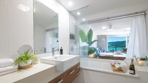 Een moderne badkamer met een grote spiegel, een wastafel en een douche.