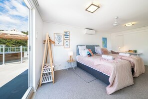 Ein Schlafzimmer mit einem großen Bett, einer Leiter, einem kleinen Tisch und Blick ins Freie.