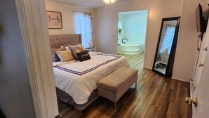 A bedroom with a bed, a bench, a ceiling fan, and a door leading to a bathroom. - Disney Vacation home 20 mins away from Parks!! (Davenport)
