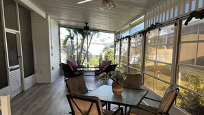 A covered patio with a table and chairs, large windows, and a view of the outdoors. - Disney Vacation home 20 mins away from Parks!! (Davenport)