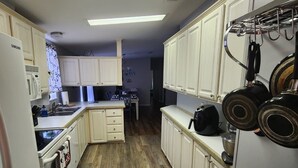 A kitchen with white cabinets, a microwave, a stove, and a sink. There is a black rug on the floor and a ceiling light. - Disney Vacation home 20 mins away from Parks!! (Davenport)