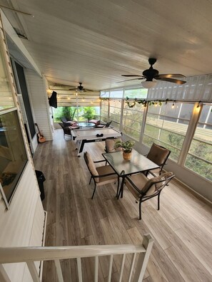 Enjoy dining or socializing in this outdoor space with tables and chairs, surrounded by lush greenery and natural light.