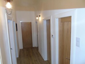 A hallway with wooden doors, white walls, and a light fixture on the ceiling.