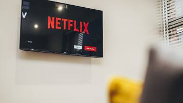 A flat-screen TV mounted on a wall displaying the Netflix logo with 'Sign in' and 'Get started' buttons.