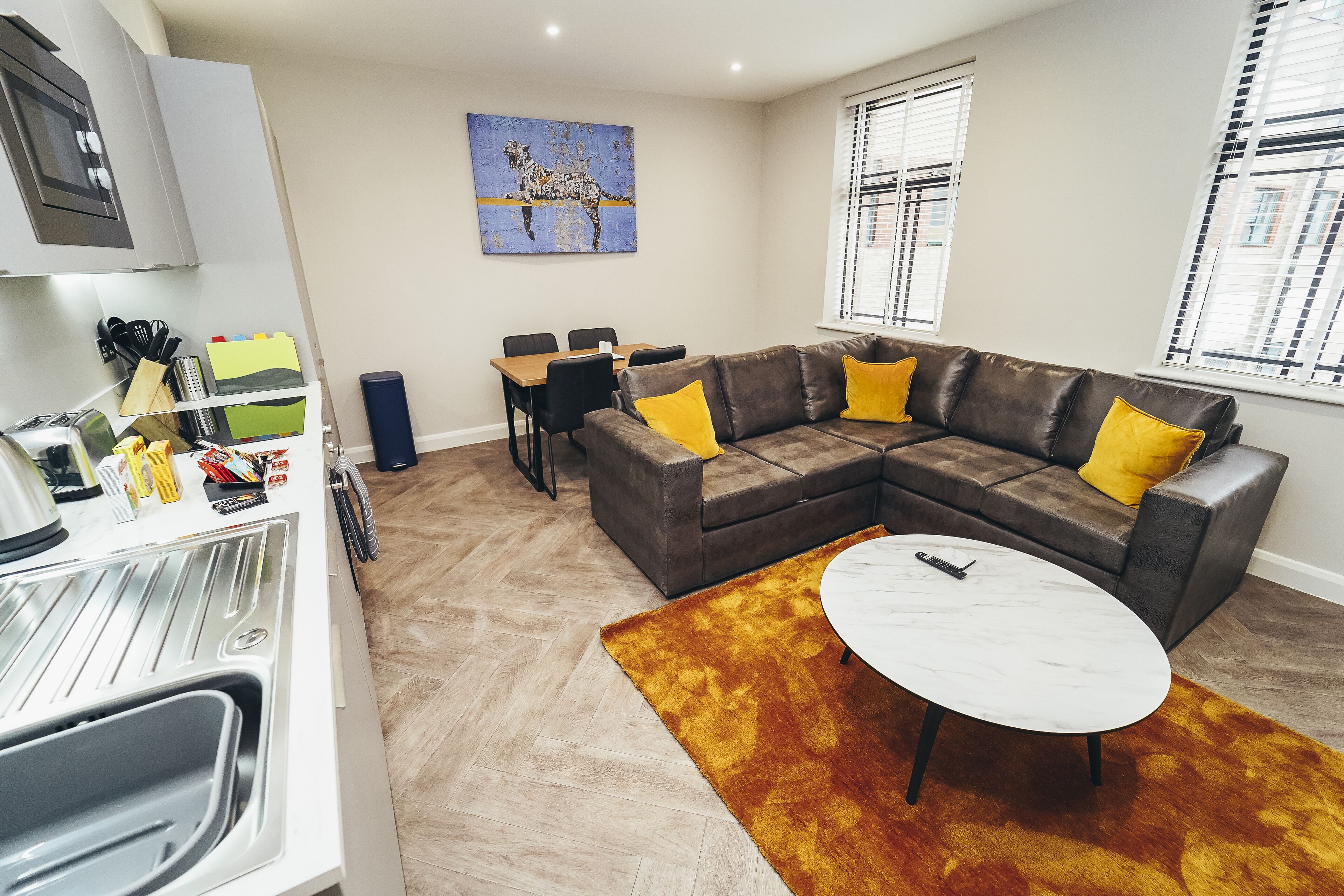 Una sala de estar moderna con un sofá modular, un comedor y una cocina con microondas.