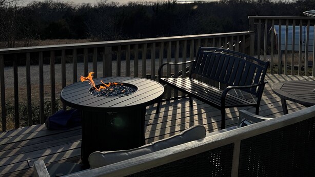 A deck with a round table and two chairs, overlooking a body of water and a distant shoreline. - Relax and Unwind in a Home overlooking Lake Texoma (Kingston)