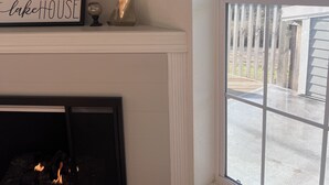 A fireplace with a sign above it, a window with a view of the outdoors, and a ceiling fan. - Relax and Unwind in a Home overlooking Lake Texoma (Kingston)