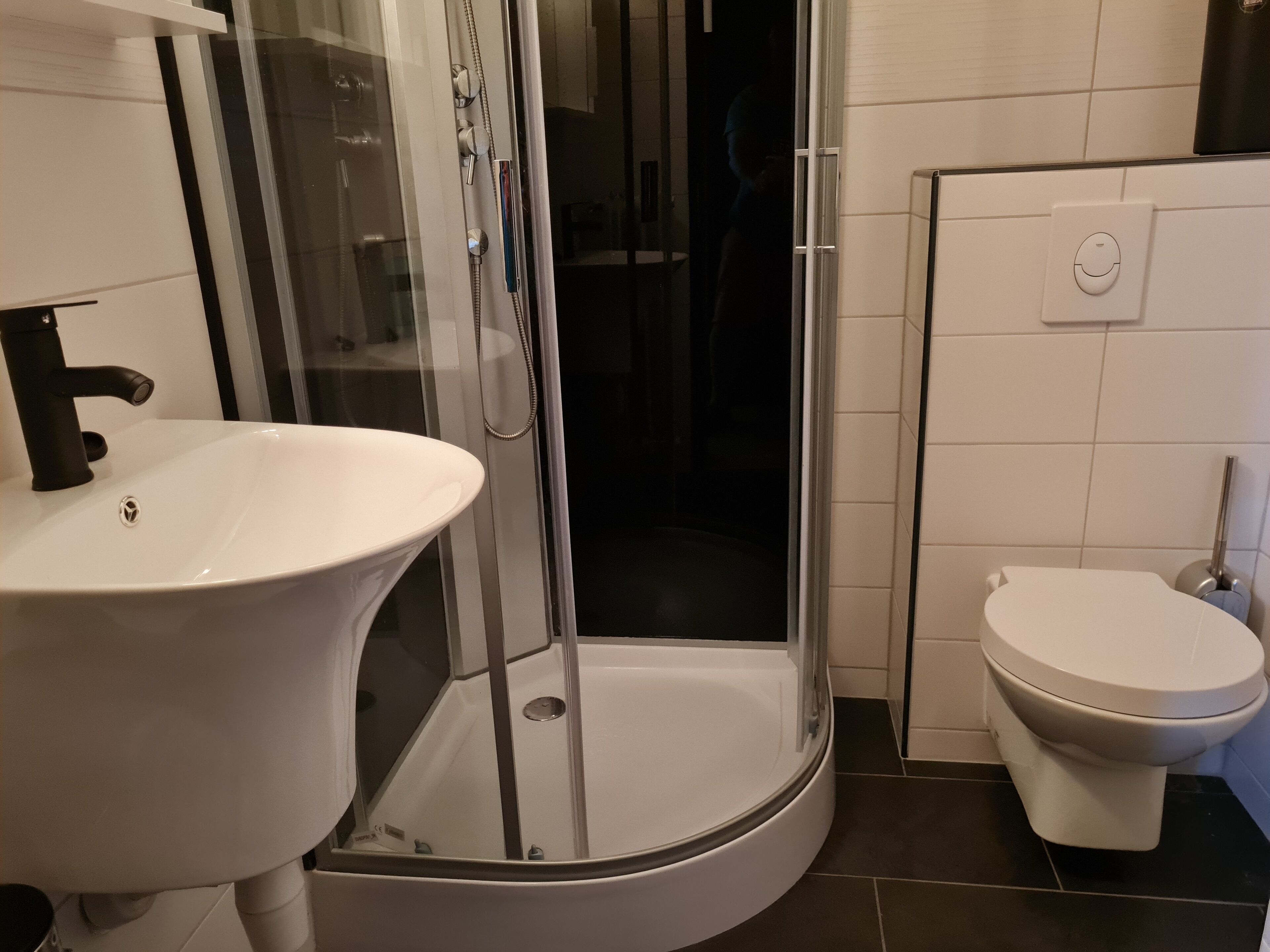 A bathroom with a white sink, a glass-enclosed shower, and a toilet.