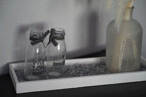 Two clear glass bottles with ribbons tied around them, placed on a tray with small pebbles.