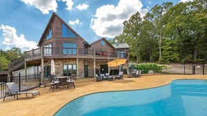 A large wooden house with a swimming pool, outdoor furniture, and a covered patio area. - 5BR Table Rock Lake Getaway |Hot Tub, Pool Games (Blue eye)