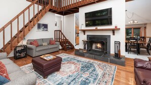 A spacious living area with a fireplace, a staircase, and a dining area.