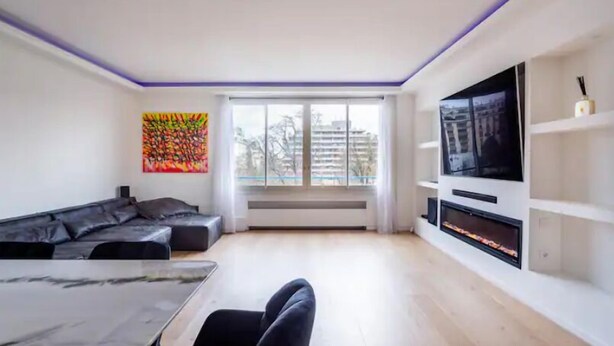 A modern living room with a sofa, a dining table, a fireplace, and a TV.