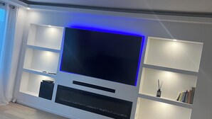 A modern living room with a flat-screen TV, built-in shelves, and a fireplace.