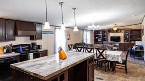 A kitchen with dark wooden cabinets, a central island with a marble countertop, and pendant lighting. - $0 Cleaning - Best for Groups and Families (Bastrop)