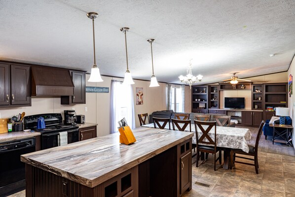 A kitchen with dark wooden cabinets, a central island with a marble countertop, and pendant lighting.