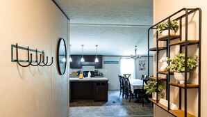 A modern kitchen with dark cabinets, a central island, and a dining area with chairs and a table. - $0 Cleaning - Best for Groups and Families (Bastrop)