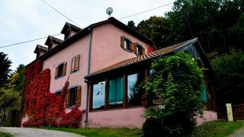 Charming two-story house with a front entrance, glass door, and wooden shutters.
