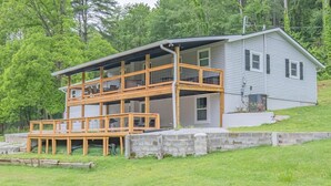 A two-story house with a wooden deck and a stone retaining wall.