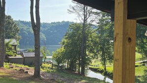 A lakeside view with a wooden deck, a small dock, and a grassy area with trees.