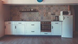 A kitchen with patterned backsplash, white cabinets, a clock, a microwave, and an oven. - House in the heart of the Périgord Vert. (Payzac)