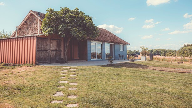 A rustic house with a stone chimney, a large tree, and a paved pathway leading to the entrance. - House in the heart of the Périgord Vert. (Payzac)