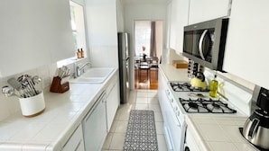 A modern kitchen with white cabinets, a stainless steel refrigerator, a gas stove, and a microwave.