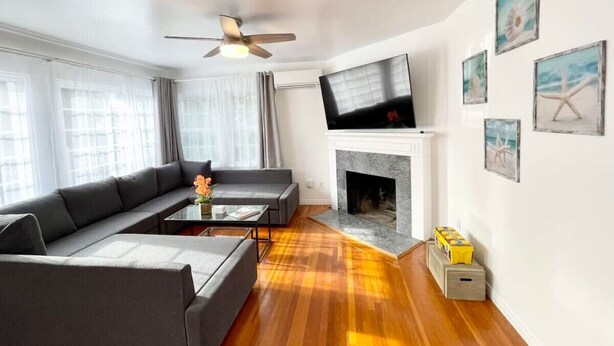 A modern living room with a sofa set, a fireplace, and artwork on the walls.