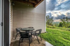 Relax on the covered patio with a round table and four chairs, surrounded by a lush lawn and scenic views.