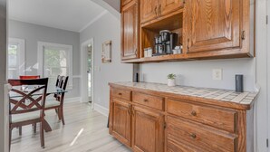 Una cocina con armarios de madera, una encimera y un comedor con sillas.