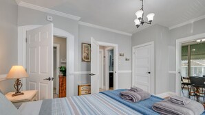 Habitación de hotel con cama, mesita de noche, lámpara, un cuadro y vista al comedor.