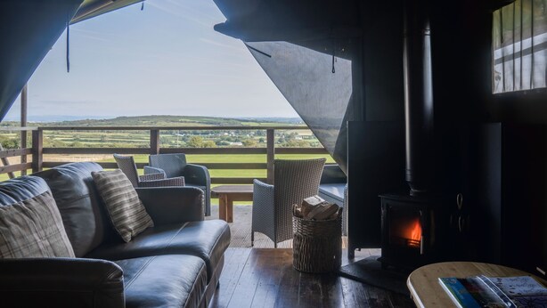 A cozy room with a leather sofa, wicker chairs, a wooden table, and a fireplace.