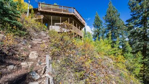 A wooden cabin with a balcony, surrounded by trees and a rocky path. - Cabin on Columbine Lake - Large deck - Hot Tub/Views  - 1 mile to Purgatory (Durango)
