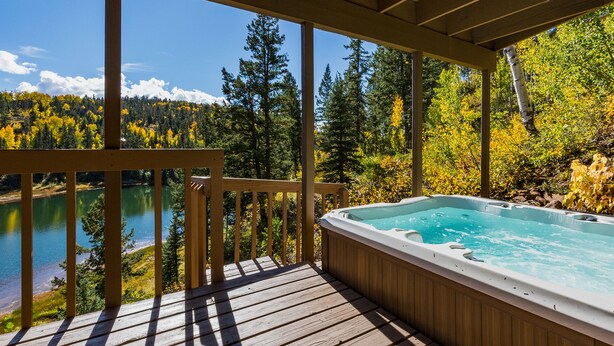 A wooden deck with a hot tub overlooking a lake and forest. - Cabin on Columbine Lake - Large deck - Hot Tub/Views  - 1 mile to Purgatory (Durango)