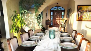 Un comedor con una mesa larga dispuesta para varias personas, rodeada de sillas con asientos acolchados.