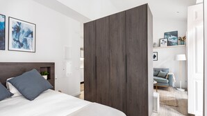 A modern bedroom with a large bed, a wardrobe, and a sofa in the background. - Studios Terra & Mar (Lisbon)