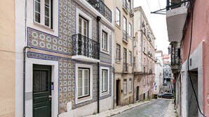 A narrow cobblestone street lined with buildings featuring traditional Portuguese tile patterns and balconies. - Studios Terra & Mar (Lisbon)