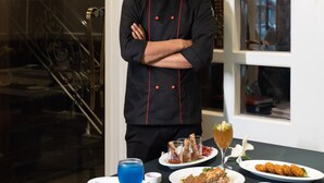 A chef standing in front of a table with various dishes and a blue drink. - Country Inn Hall Of Heritage Amritsar (Amritsar)