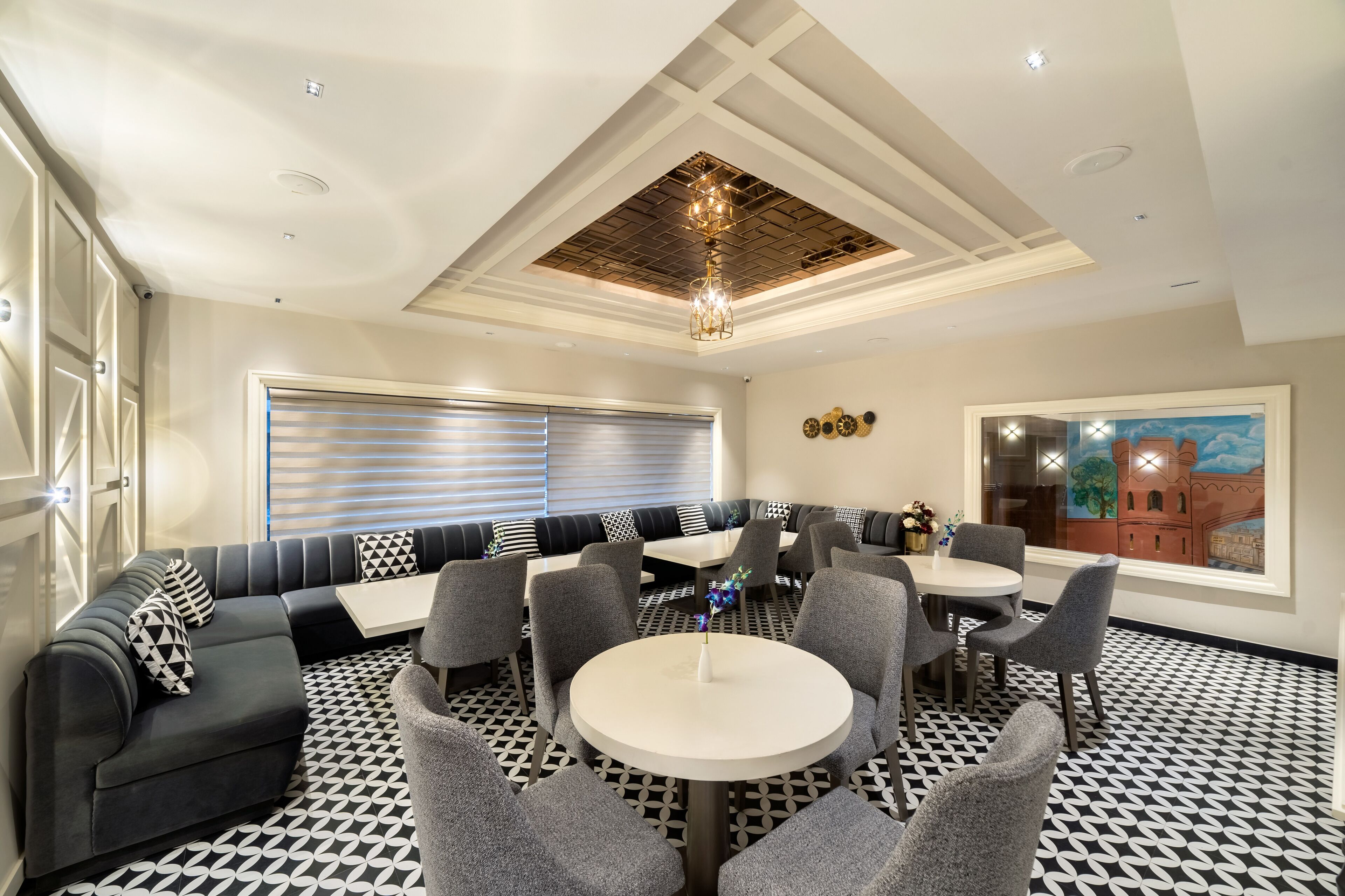 Un espace repas moderne avec une table ronde, des chaises grises et un sol à motifs noir et blanc.
