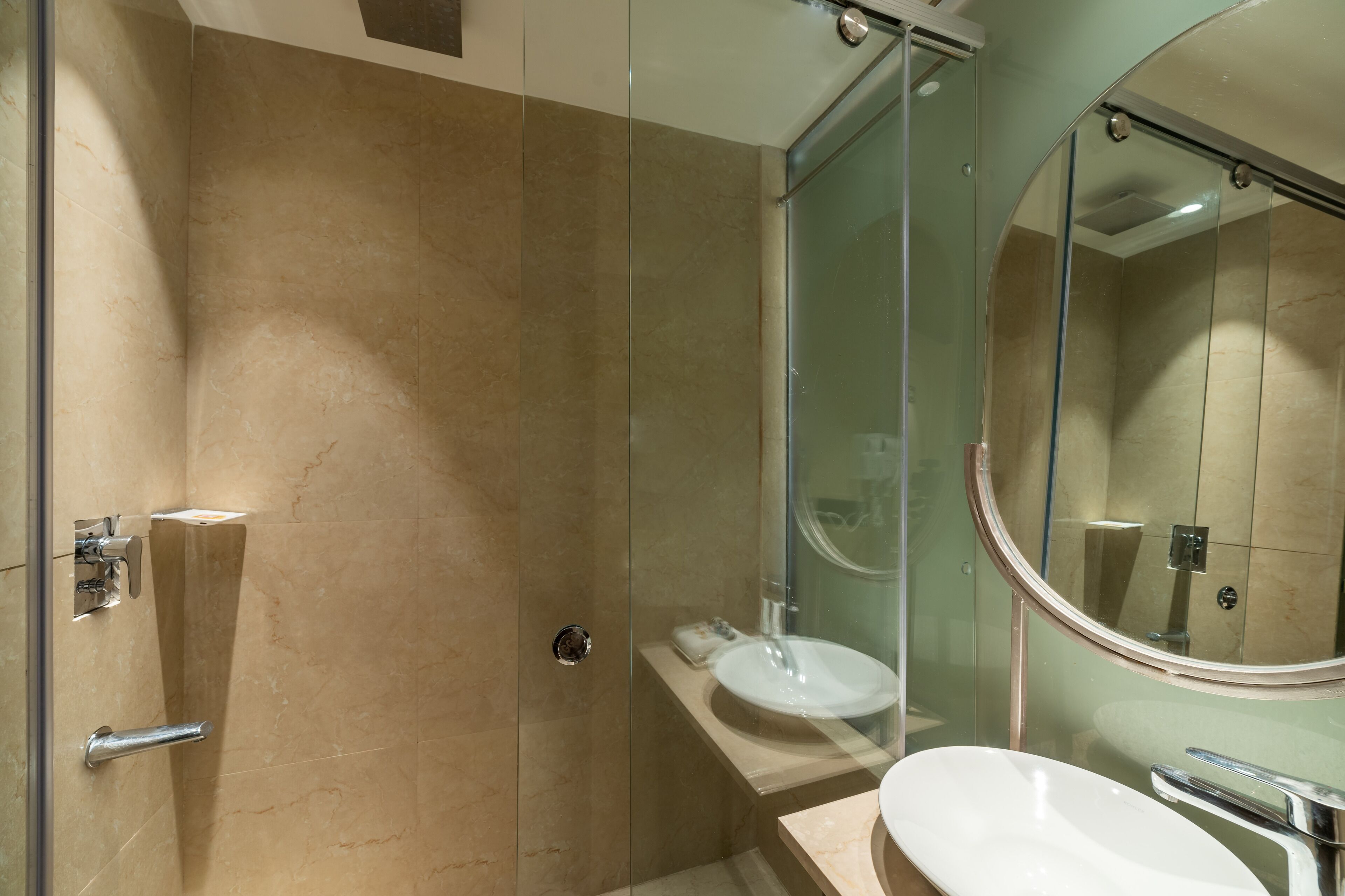 Un baño moderno con ducha envuelta en vidrio, un lavabo blanco y un espejo grande.