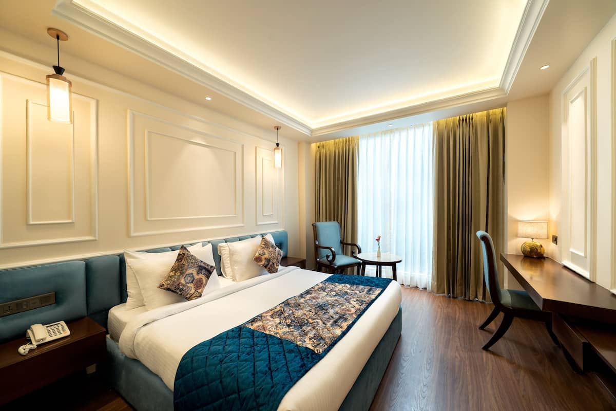 A hotel room with a large bed, bedside tables, a desk, and a chair.